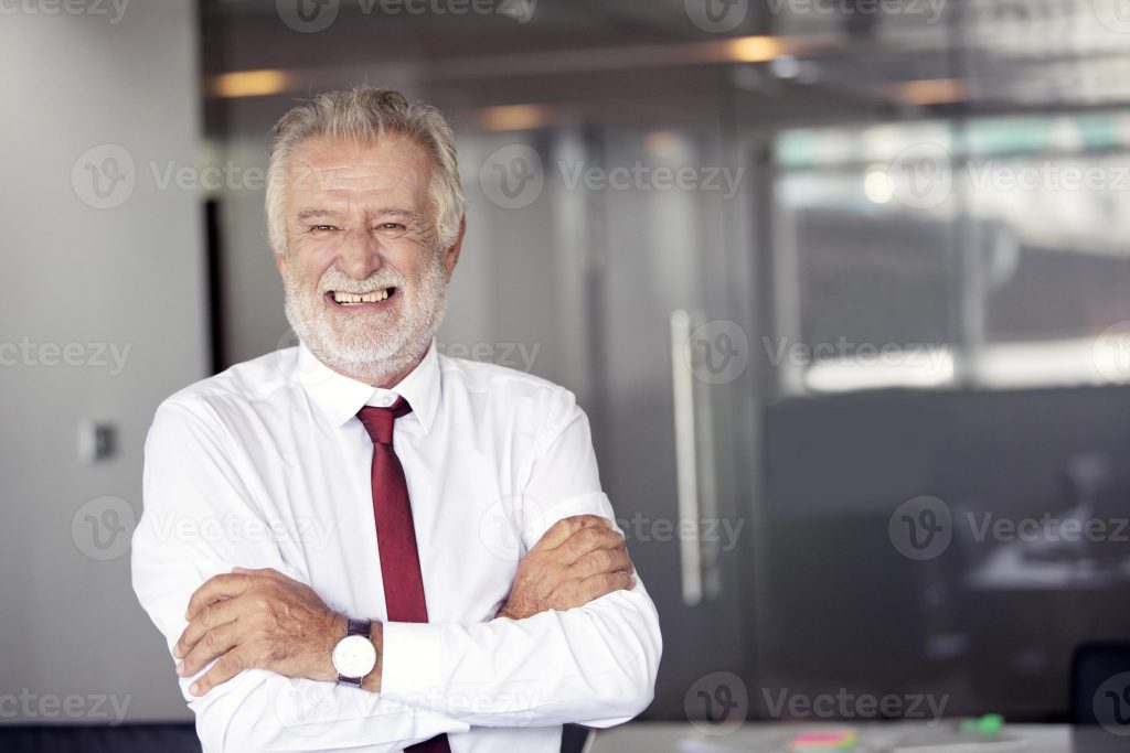 happy handsome old businessman standing and smiling in office photo